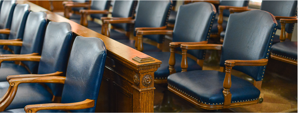 Photograph of rows of empty chairs where the jury sits, inside a courtroom. Trial by jury is a right guaranteed by the PA Constitution. Citizens randomly selected for jury duty become the fact-finders in cases presented to them. By giving equal weight to diverse voices, a jury represents the common sense of ordinary people.